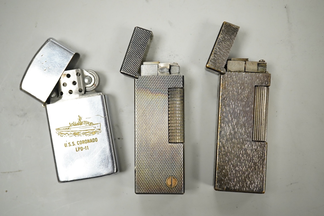 Two Dunhill rollagas silver plated lighters, barley pattern and rusticated 6.5cm long and a U.S.S. Coronado LPD-11, zippo lighter (3)